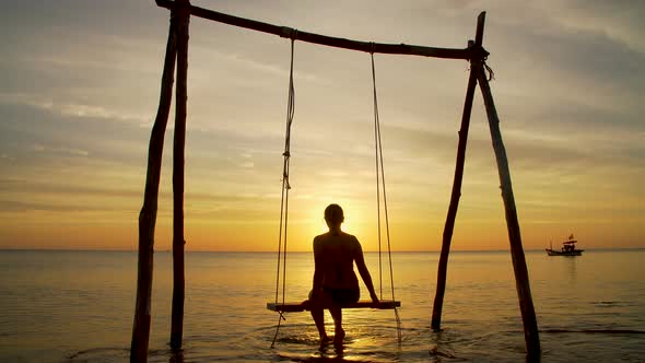 Girl on a Swing By the Seashore on Sunset