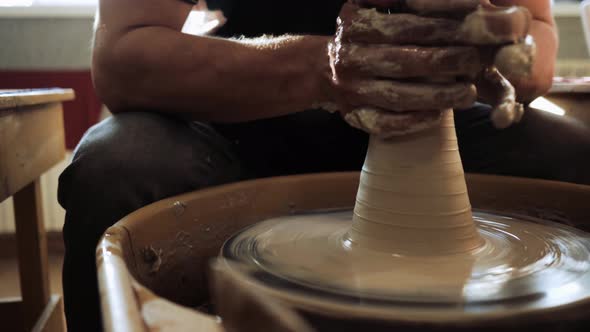 A Young Male Potter Works on a Potter's Wheel with Clay