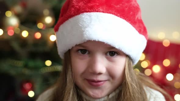 Close Up Portrait of Happy Surprised Little Girl Wearing Santa Hat on Background of Decorated