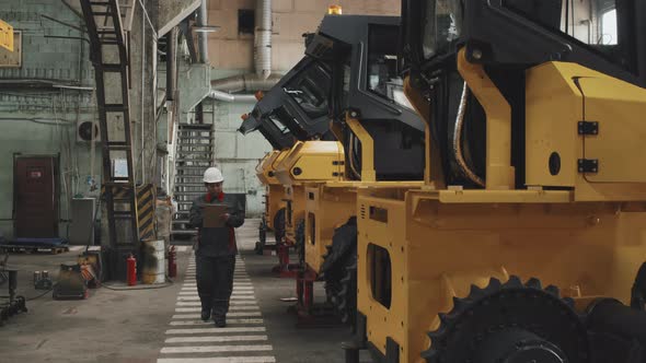 Woman Inspecting Tractors at Plant