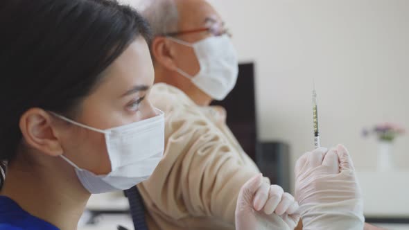 Caucasian doctor wear protective face mask, give treatment to Senior elderly man disabled patient.