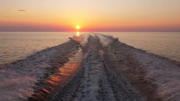 Boat run on calm lake, camera look back to wake and sunset