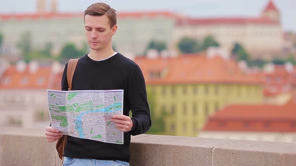 Man Tourist with a City Map and Backpack in Europe. Caucasian Boy Looking with Map of European City