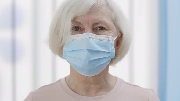 Close Up View of Senior Woman in Medical Protective Mask Raising Head and Looking to Camera