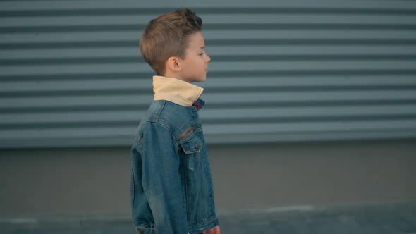 Alone Little Boy Is Walking Down the Street and Thinking. Face of a Little Serious Sad Boy Being