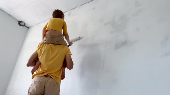 A Father and Son Both Wearing a Yellow Tshirt Paint the Wall Using a Roller Painter