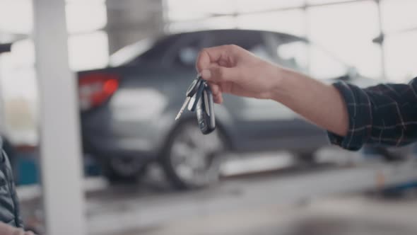 Unrecognizable Auto Mechanic Returning Car Keys to Client