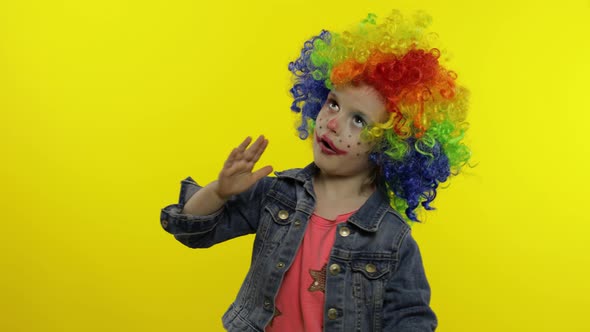 Child Girl Clown in Wig Making Silly Faces. Having Fun, Shows the Movements of Mime. Halloween