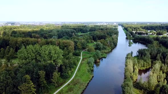 Drone flying over the canal in the forest with a village in the background. Dronten, Netherlands.