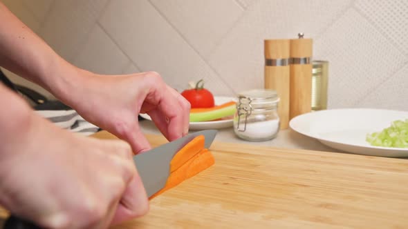 Woman Chopping Carrot in Kitchen Close Up