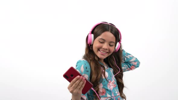 Cheerful Dancing Child Hold Cell Phone Listening Music in Headphones with Peace Gesture Music Lover