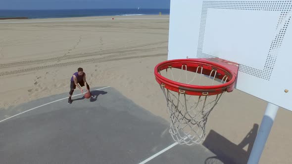 A man does a slam dunk while playing one-on-one basketball hoops on a beach court