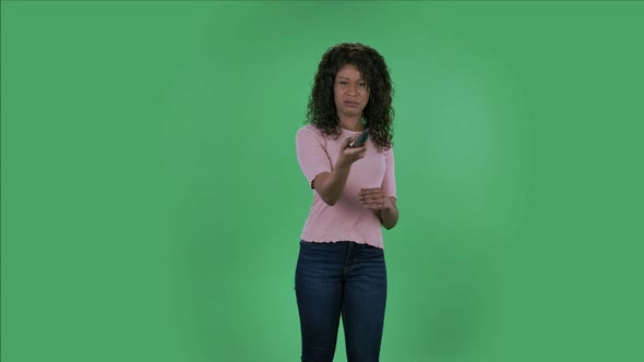 Portrait of Beautiful African American Young Shocked Woman with TV Remote in Her Hand, Switching on