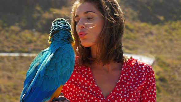 Parrot Standing in Females Hand as She Pets the Macaw on a Sunny Day