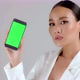 Beautiful Asian businesswoman showing smartphone with green screen - VideoHive Item for Sale