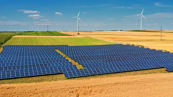 Solar panels and wind turbines in summer on field