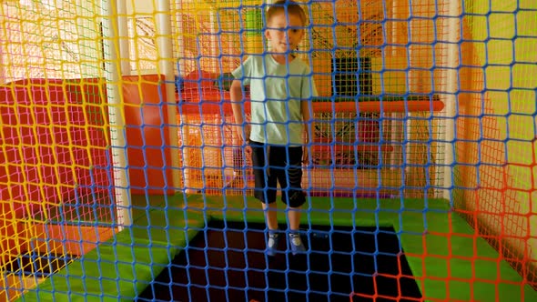 Slow Motion of Cheerful Little Boy Jumping on Trampoline and Playing on Playground