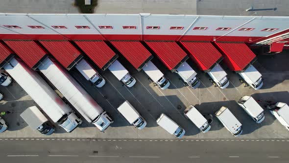 Aerial top view of an industrial warehouse loading dock, where many delivery vans and trucks.