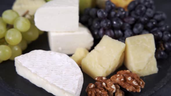 Different Types of Cheese Grapes and Walnuts on a Rotating Plate