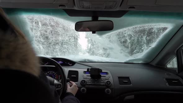 Couple Cleaning Snow From Car Windshield