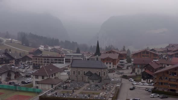 Aerial of  Saint-Jean-de-Sixt church in French Alps, scenery of recreational village with wooden bui