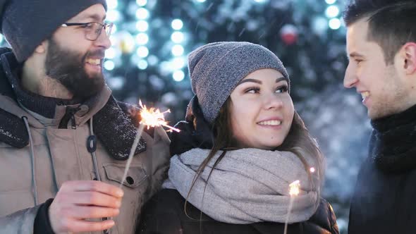 Close-up of Friends Celebrating New Year Outdoors, Keeps Sparklers, Lights in the Blur in the