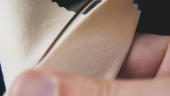 Person Cleans Glasses with Beige Napkin on Dark Background