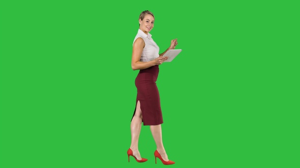 Woman walking using digital tablet and talking to camera