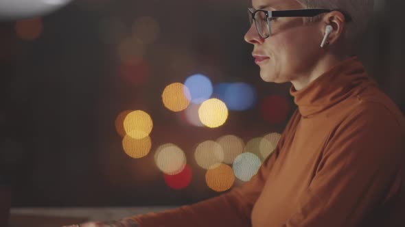 Female Office Worker Typing on Laptop in Evening