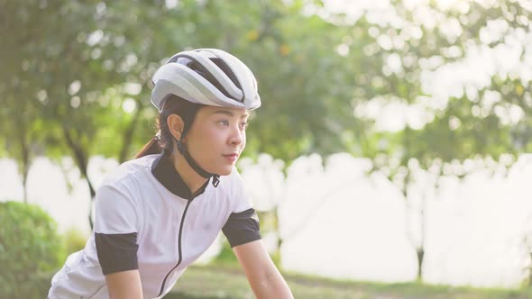 Asian young beautiful woman exercise by riding bicycle for health in the evening in public park.