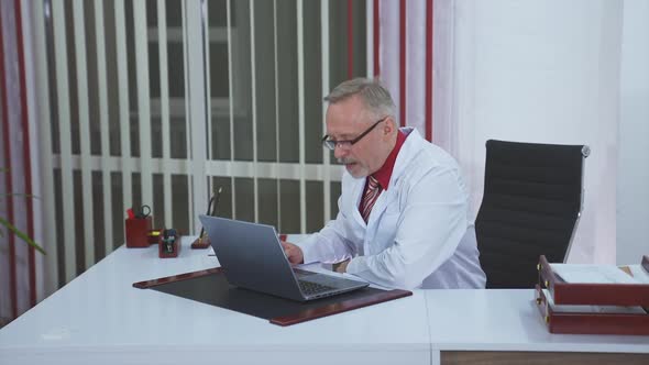 General practitioner sitting at his desk in medical office. Discussing medical issues.