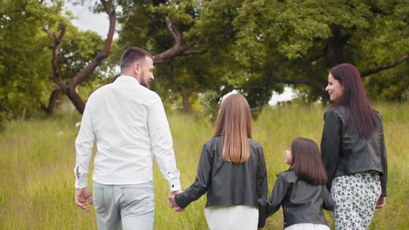 Attractive Pregnant Mother And Father Holding Hands with Her Two Little