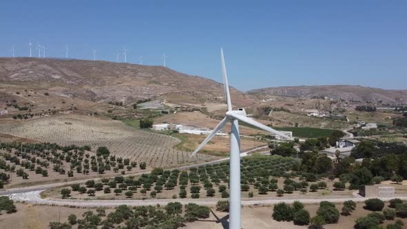 Wind Energy Converter In The Wind Farm With Landscape Of Olive Groves In The Background In Agrigento