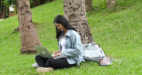 Side View Of Woman Sitting In Park And Using Laptop Computer