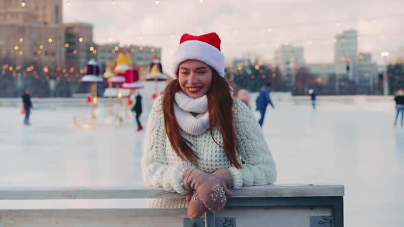 Young Smiling Woman Santa Hat Ice Skating Outside on Ice Rink Dressed White Sweater