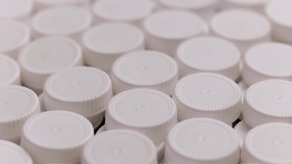 Looped Spinning Closeup Background of White High Density Polyethylene Plastic Bottle Caps