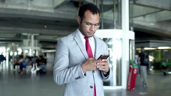 Businessman Using Smartphone at Railway Station