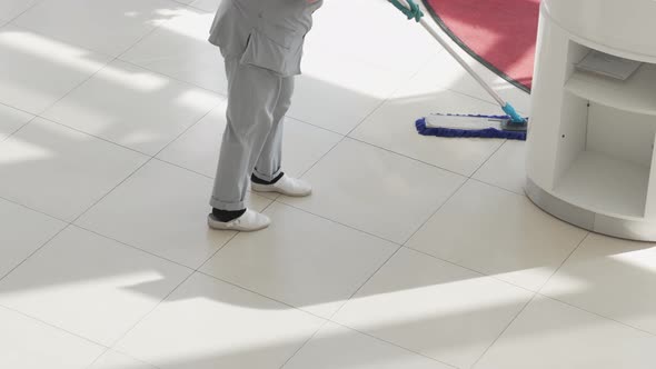 a Female Cleaner Washes Floors with a Mop in the Office or Sales Floor