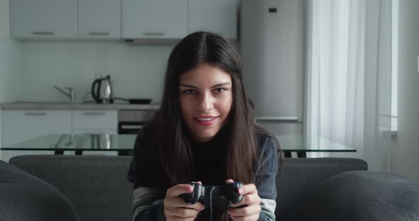 Beautiful Excited Young Gamer Girl Sitting on a Couch Playing and Winning in Video Games on Sofa