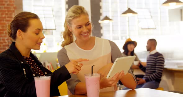 Female executives using digital tablet at cafe counter 4k