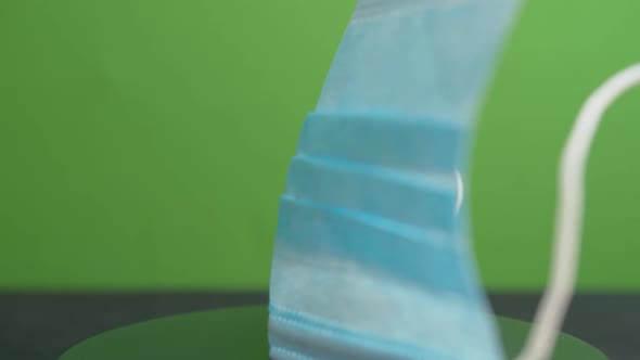 Close-up of a disposable surgical mask that rotates in front of a green screen