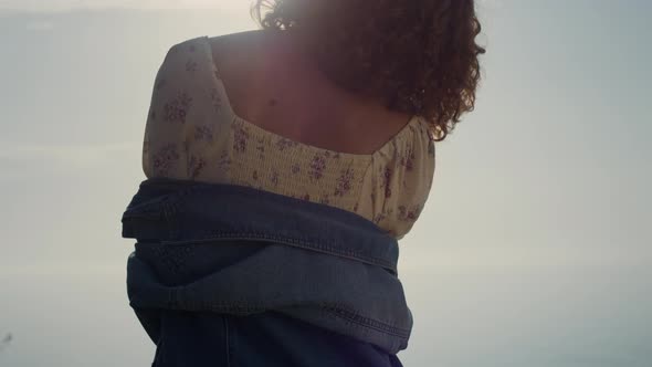 Unknown Girl Standing Backwards on Beach Enjoying Bright Evening Sunlight