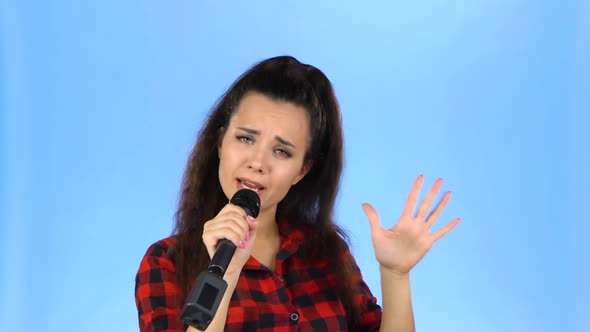 Lady Sings Into Microphone in a Studio on a Blue Background