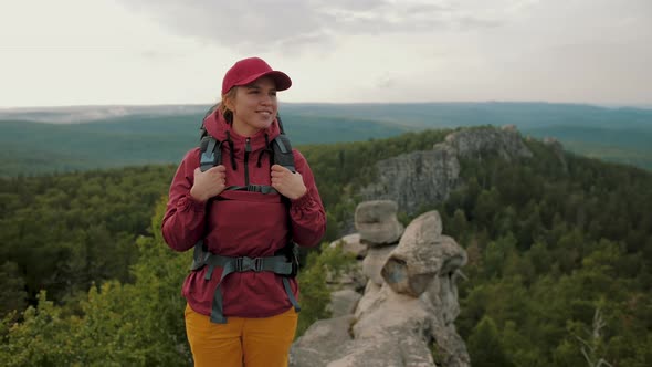 Woman Hiker with Backpack Standing on Top of Mountain Peak Admiring Nature View