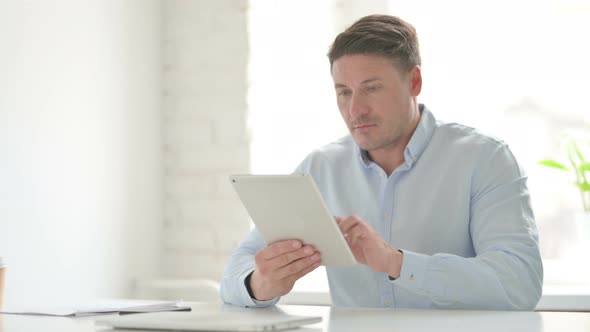 Man Celebrating Success on Tablet in Office