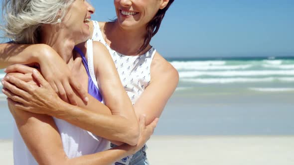 Mother and daughter embracing each other at beach