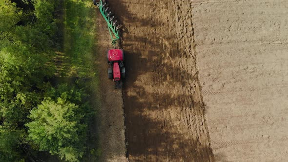 Farmer on a Tractor Prepares Farmland Near the Forest for the Next Year. Modern Agribusiness