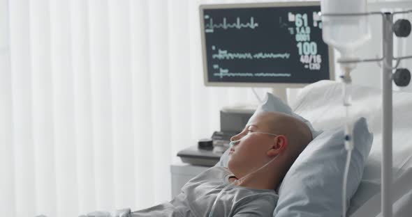 Teenage Bald Boy Lying in Hospital with Oxygen Tube