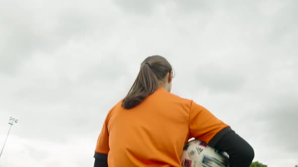 Female referee walking on the football pitch holding the soccer ball - slow motion