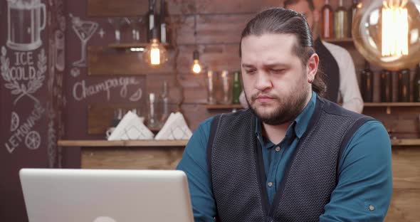 Serious Young Freelancer Works Remotely on His Laptop